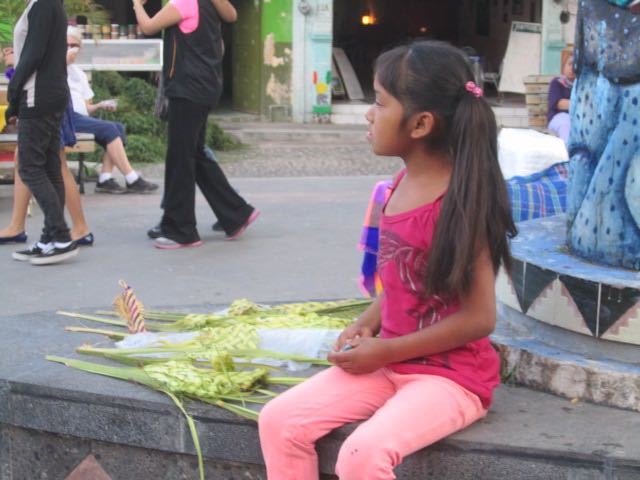 Girl selling palm religious symbols